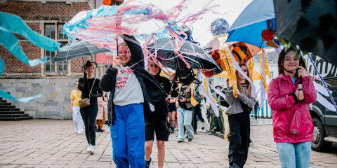 Kinderen dragen paraplu's versierd met dieren errop op de grote parade die door de stad trekt