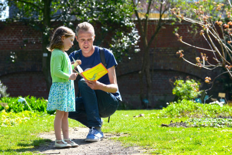 Papa en dochter in de tuin. Ze lezen de bezoekersgids van het museum. 