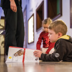 Een jongen bekijkt een papieren brochure in het museum