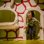 Een jongen komt uit een deurtje van één van de huisje in de 1001 Stippen-tentoonstelling over paddenstoelen